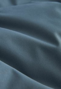 Țesătură de catifea albastră cu o textură netedă, prezentând pliuri fine și un luciu subtil, reflectând lumina pe întreaga sa suprafață.