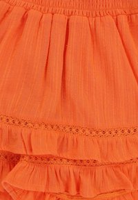 Oranje gerimpelde rok van lichte stof met een smocktail. Decoratieve geborduurde accenten tussen de lagen.