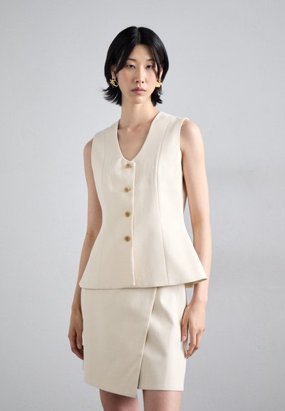 Beige tailored vest with a v-neckline and five gold buttons, paired with a matching knee-length skirt featuring a diagonal cut.