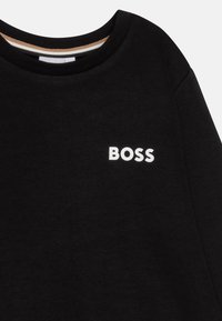 Sudadera negra con un escote redondo y un pequeño logo "BOSS" en blanco. El material parece suave con una textura lisa, con un interior del cuello en contraste.