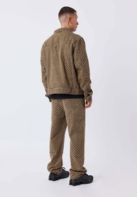 Giacca marrone con motivo e pantaloni abbinati realizzati in tessuto testurizzato, con un design sottile e abbinati a calzature nere.