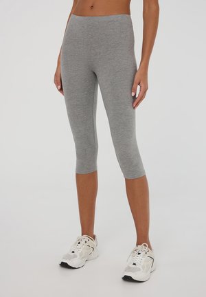 Leggings capri grigi realizzati in un tessuto morbido e elasticizzato. Vita alta e silhouette aderente. Indossate con sneakers bianche con dettagli in rete.