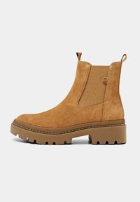 Botte Chelsea en daim beige avec panneau latéral élastique, languettes de tirage, semelle épaisse à crampons et petit talon carré.