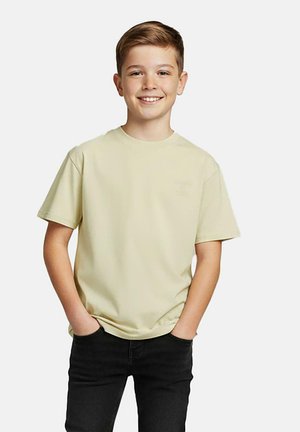 Lichtgele katoenen T-shirt met een ronde hals en korte mouwen, voorzien van een klein logo aan de linkerkant, gedragen met een donkere spijkerbroek.