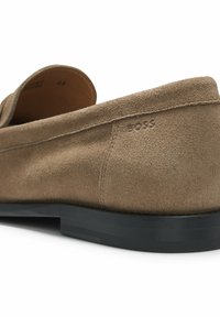Brown suede loafer with black sole, showing stitching details and embossed brand name "BOSS" near the heel.