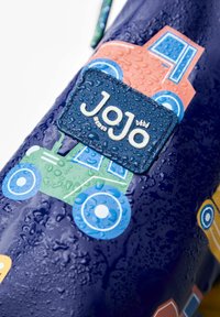 Tähtsin saduvaba sinine vett-tõrjuv kott, millel on värvilised sõiduki mustrid (roheline, sinine ja oranž). Omab tekstuuriga logo sildiga "Jojo" valge tekstiga.