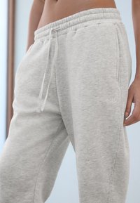 Ljusgrå mjukisbyxor i mjukt bomullsmaterial, med elastisk midjeband, dragsko och sidofickor. Diskret logotypdetalj.