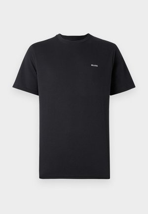 Camiseta negra de manga corta con cuello redondo y pequeño logo blanco de "Hollister" en el lado izquierdo del pecho, sobre un fondo liso.