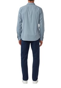 Lichtblauw geblokt overhemd met lange mouwen, gecombineerd met marineblauwe broek en witte sneakers; zichtbare stiksels en knoopdetails.