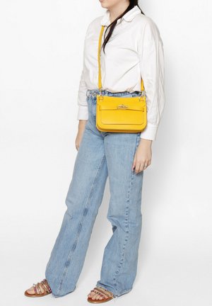 Borsa a tracolla gialla in pelle con forma rettangolare, tracolla regolabile, hardware in metallo e tasca frontale con patta. Superficie textured.
