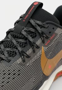 Nike Pegasus Trail 5 shoe in black with gray and white striped pattern, features orange logo, textured mesh upper, and black laces.