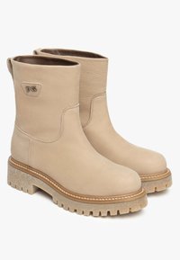 Stivaletti alla caviglia in pelle beige con una texture liscia, punta arrotondata, dettagli cuciti e una suola chunky bicolore. Accento con logo vicino alla caviglia.