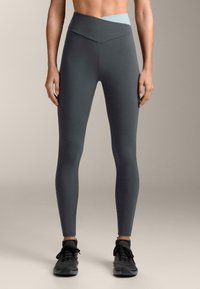 Colanți cu talie înaltă, de culoare gri închis, cu o bandă contrastantă albastru deschis; material elastic, design mulat, textură fără cusături.