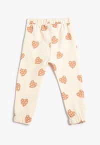 Leggings de color crema con cintura elástica, que presentan formas de corazón en color óxido con lunares blancos repetidos. Dobladillos recogidos en los tobillos.