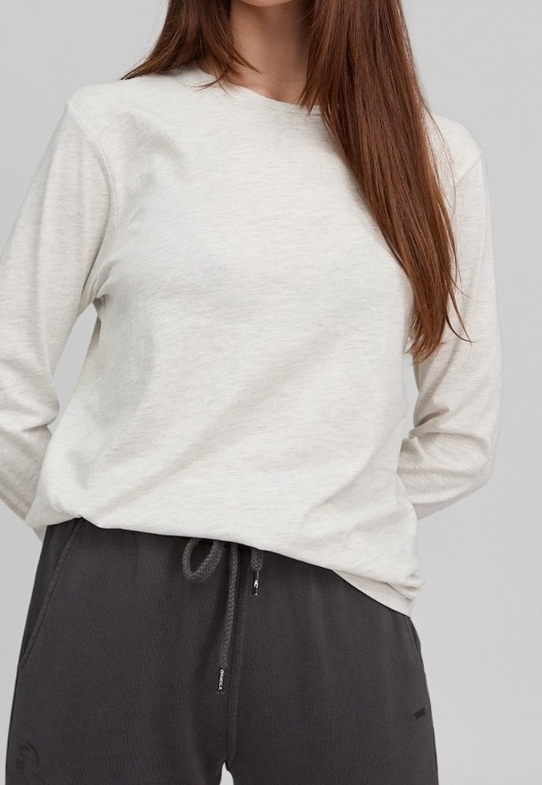 Lys grå langærmet top i et blødt materiale, med en rund halsudskæring og afslappet pasform, parret med mørke grå sweatpants med snørre.