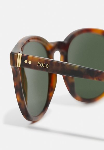 Skilpaddebrune solbriller med grønne linser, med tykke rammer. Gullakenter og "POLO"-logo på stangen. Glatt, polert tekstur.