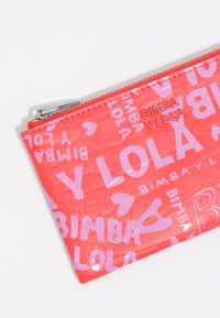 Różowa teksturowana torba PVC z błyszczącym fioletowym tekstem i sercami, z metalowym uchwytem do zamka błyskawicznego oraz wytłoczonym detalem logo.