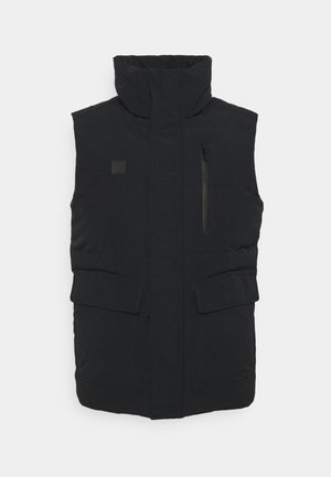 Chaleco acolchado negro con cuello alto, bolsillo frontal con cremallera y dos bolsillos frontales con solapa. Textura de tela lisa, diseño minimalista.