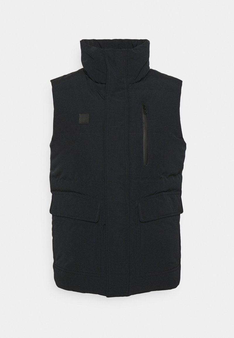 Chaleco acolchado negro con cuello alto, bolsillo frontal con cremallera y dos bolsillos frontales con solapa. Textura de tela lisa, diseño minimalista.