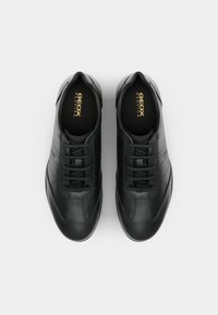 Baskets en cuir noir avec une texture lisse, bout rond, design à lacets et détails subtils sur les côtés. L'intérieur arbore le logo "GEOX RESPIRA".