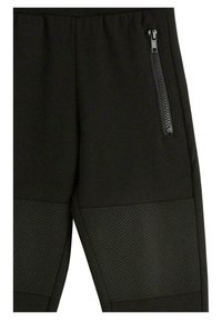 Schwarze Jogginghose mit einem strukturierten Mesh-Einsatz und einer seitlichen Reißverschlusstasche, entworfen in einer figurbetonten Form mit elastischem Bund.