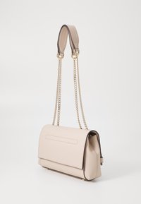 Beige faux lædertaske med en glat tekstur, guldkæde-strop og flaplukning. Har en baglomme og kontrasterende mørke kanter.