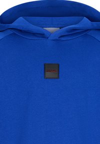 Felpa blu con un patch logo quadrato nero etichettato "RETOUR", con una texture morbida e un design classico che include un cappuccio con cordini.
