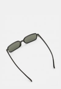 Czarne prostokątne okulary przeciwsłoneczne z ciemnymi soczewkami, smukłymi ramionami i błyszczącym wykończeniem. Design charakteryzuje się minimalną ilością elementów metalowych i kanciastymi krawędziami.