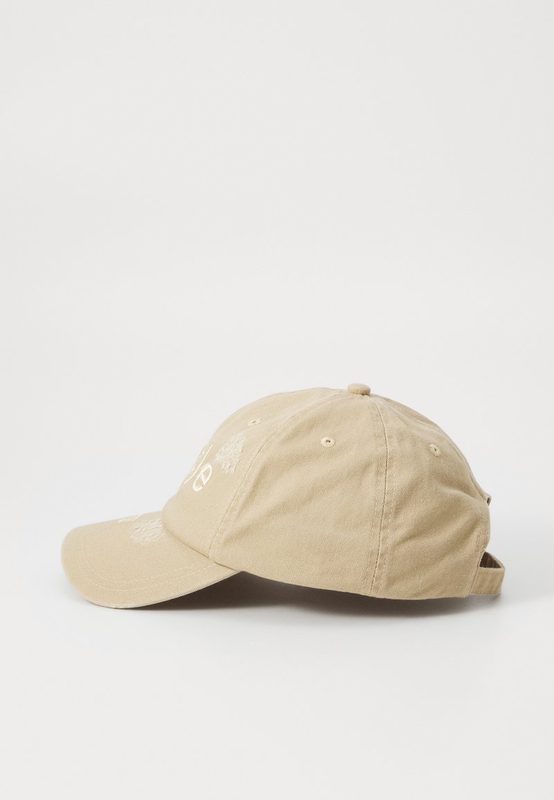 Beige cotton baseball cap with a curved brim, embroidered design on the front, adjustable strap at the back, featuring ventilation eyelets.