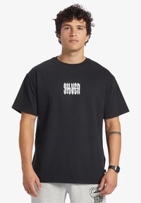 Black cotton t-shirt with short sleeves and a crew neck, featuring a white stylized graphic design on the chest. Simple and casual fit.