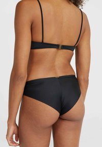 Set de bikini negru cu un design simplu, prevăzut cu închidere cu clips și bretele subțiri. Textură netedă, cu detalii minime. Vedere din spate.