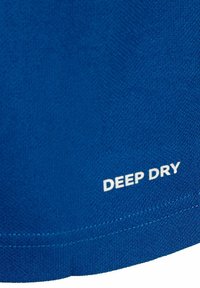 Camiseta de tela azul con una superficie texturizada. Presenta el texto blanco "DEEP DRY" impreso cerca del dobladillo. Costuras visibles.