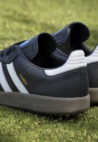Granatowe skórzane sneakersy z białymi paskami i złotym napisem "SAMBA". Teksturowana szara gumowa podeszwa i wyściełane akcenty na pięcie.