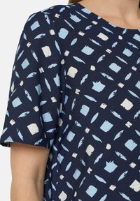Kurzärmliges navy Hemd mit einem Muster aus hellblauen und weißen abstrakten Formen, ausgestattet mit einem runden Halsausschnitt und einem strukturierten Stoff.