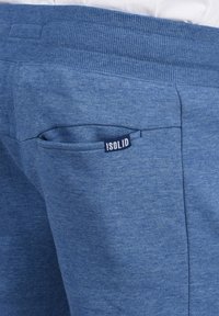 Jogging in cotone blu con vita a coste, tasca laterale con etichetta "ISOLID" visibile e una texture morbida.