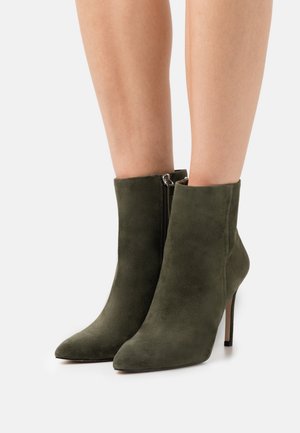 Enkellaarsjes van olijfgroen suède met een spits toelopende neus en een ritssluiting aan de zijkant, voorzien van een dunne hak en een gladde textuur.