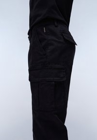 Czarne spodnie cargo z boczną kieszenią, wytrzymałą tkaniną i luźnym krojem, z widocznym przeszyciem i subtelną metką z logo.