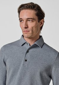 Graues Langarm-Poloshirt mit Kragen, vier dunklen Knöpfen und weicher Textur. Eng anliegendes Design mit glattem Stofffinish.