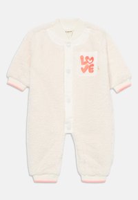 Ullvennlig kremfarget jumpsuit med hvit knappet front, en rosa lomme med teksten "KJÆRLIGHET" i glitter, og ribbede mansjettdetaljer.