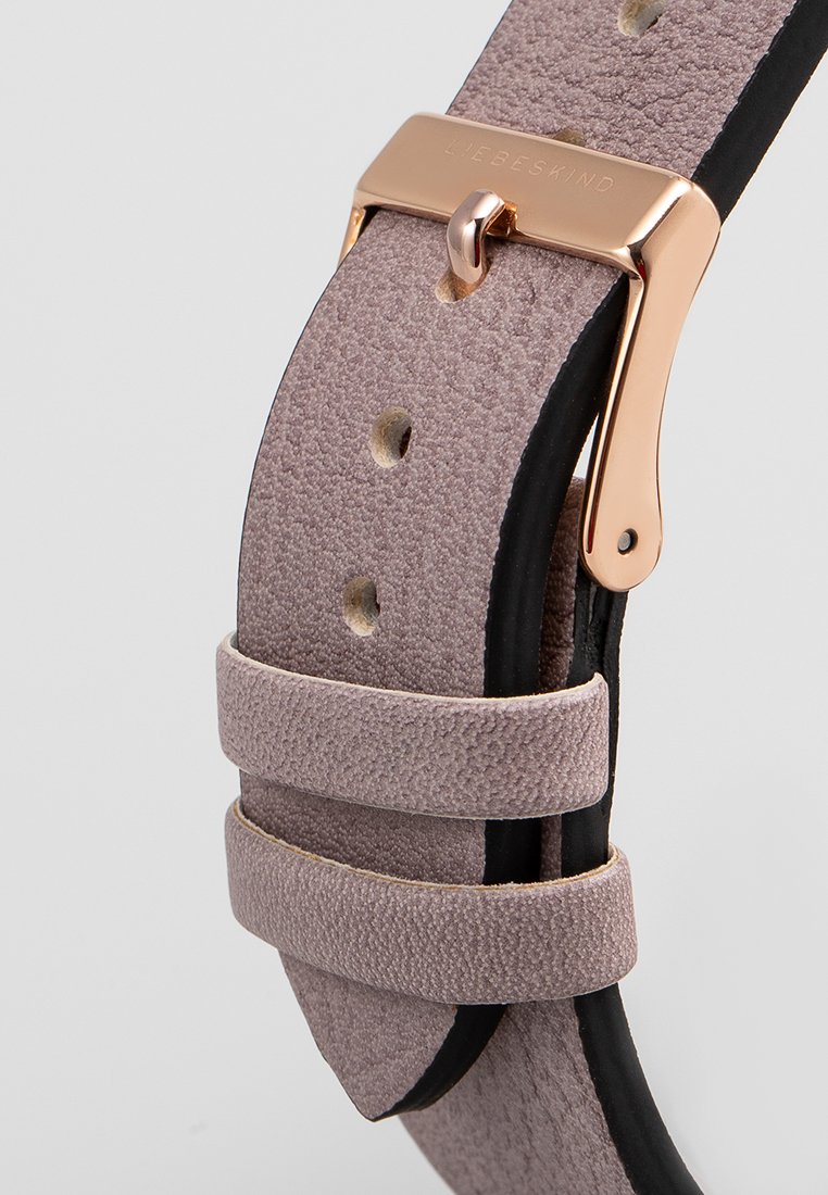 Rosenfarbener Lederuhrengürtel mit strukturierter Oberfläche, verstellbar mit einer glänzenden goldenen Metallschnalle, die mehrere Löcher für die Größenanpassung aufweist.