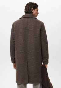 Abrigo de cuadros marrones con un amplio cuello, mangas largas y puños abotonados. La textura parece suave, con un ajuste entallado y un diseño de longitud media.