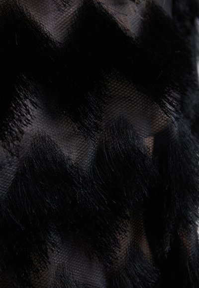 Must mustri riie, millel on tekstuuriga siksakimuster, mis on valmistatud pehmest, pikast kiust. Kujunduses on ühendatud läbipaistvad ja tihedad alad kontrasti saavutamiseks.