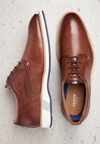 Chaussures en cuir brun avec lacets, semelle blanche et marine, et une finition lisse. Présente un accent gris au talon et une semelle intérieure en cuir.
