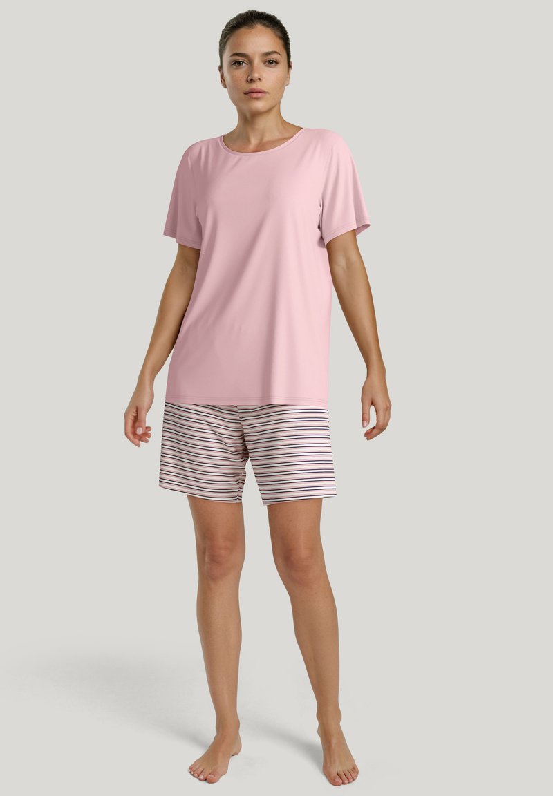 Lichtroze top met korte mouwen, gecombineerd met gestreepte shorts in wit, marineblauw en kastanjebruin. Zacht materiaal, ontspannen pasvorm en shorts tot halverwege de dij.