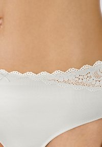 Witte katoenen slipjes met een delicate kantafwerking met golvende randen en bloemvormige uitsparingen langs de taille. Zachte textuur, aansluitend ontwerp.