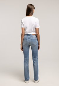 Jasnoniebieskie dżinsy o wąskim kroju, z tylnym szwem oraz dwoma tylnymi kieszeniami. W połączeniu z prostą białą koszulką.