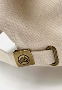 Correa de lona beige con una superficie texturizada, con un clasp de metal bronce que presenta un emblema circular que representa un continente y una estrella.