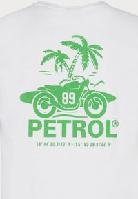 Valkoinen t-paita, jossa on vihreä grafiikka moottoripyörästä, surfilaudasta, palmupuista, numerosta 89 ja "PETROL" -tekstistä.