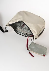 Beige Nylon Tasche mit einem Reißverschluss, ausgestattet mit einer Innentasche und einem kleinen abnehmbaren tealfarbenen Beutel mit rotem Tragegurt und Reißverschluss.