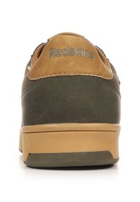Sneaker verde in suede con tallone in pelle beige, caratterizzato dal marchio "Redskins" e una suola in gomma. Texture liscia e design casual.